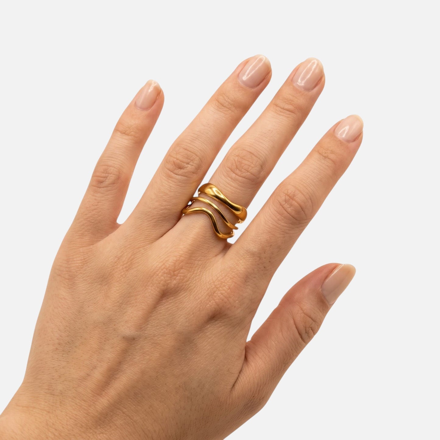 Lässiger Beach-Look: Eine Hand trägt den goldenen Nalu Wellenring im Sommer-Style.