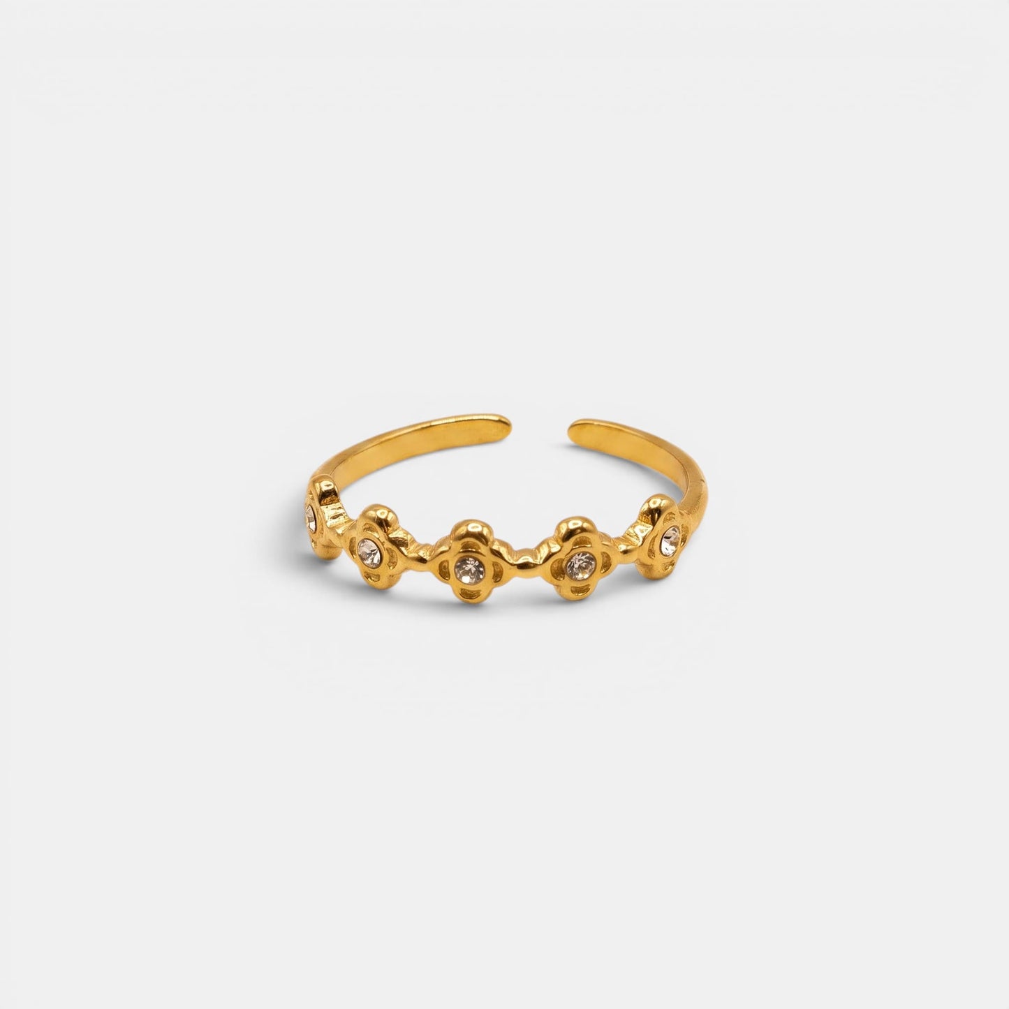 Goldener Estella Ring mit kleinen, aneinandergereihten Sterne-Elementen auf einem nahtlosen cremefarbenen Hintergrund.