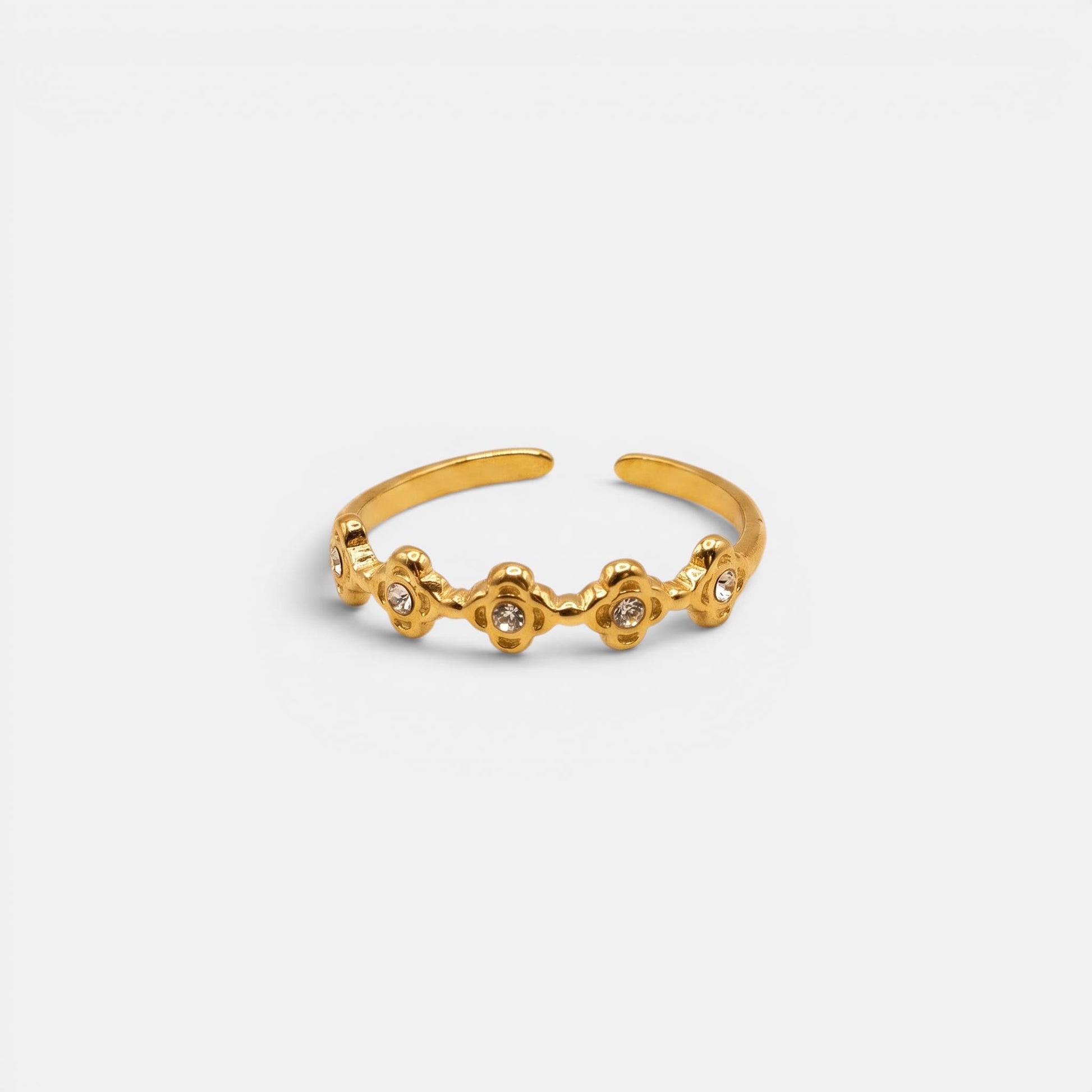 Goldener Estella Ring mit kleinen, aneinandergereihten Sterne-Elementen auf einem nahtlosen cremefarbenen Hintergrund.