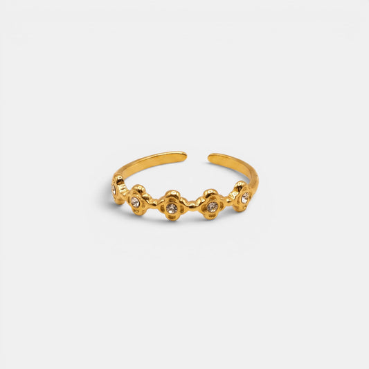 Goldener Estella Ring mit kleinen, aneinandergereihten Sterne-Elementen auf einem nahtlosen cremefarbenen Hintergrund.