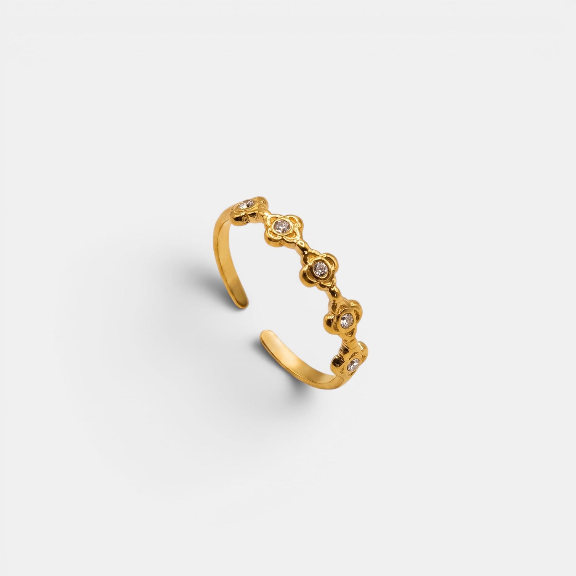 Goldener Estella Ring mit kleinen, aneinandergereihten Sterne-Elementen auf einem nahtlosen cremefarbenen Hintergrund.